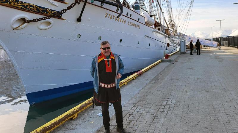 man standing in front of an old sailboat